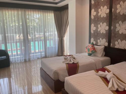 a hotel room with two beds and a window at The Sand Beach Pattaya in Na Jomtien