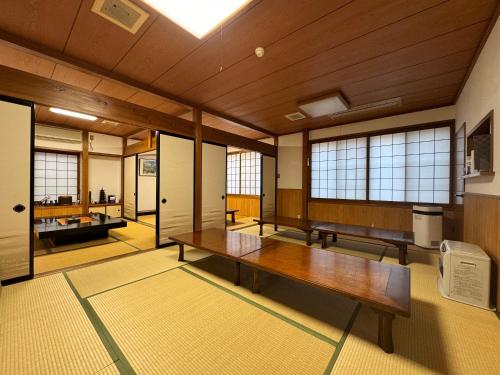 a large room with a wooden table and windows at Shiroyamasou in Asahi
