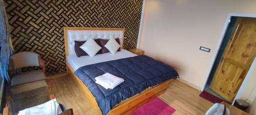 - une petite chambre avec un lit doté d'une couette et d'oreillers bleus dans l'établissement Paradise Point Hotel & Restro, à Darjeeling