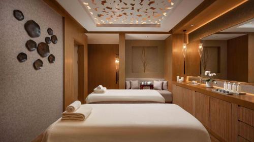 a hotel room with three beds and a mirror at Shangri-La Nanjing in Nanjing
