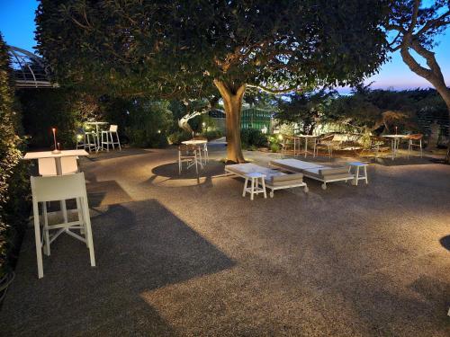 a group of tables and chairs under a tree at Villa Dune Luxury Roof Top Pool Wellness in Gallipoli