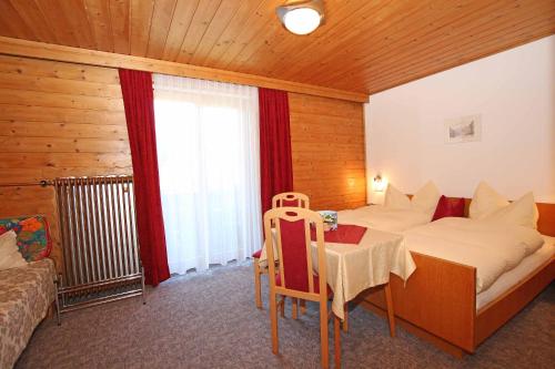 a bedroom with a bed and a table and a window at Pension Delacher in Ried im Oberinntal