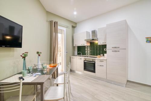 a kitchen with white cabinets and a table with chairs at Eclisse House Few Steps From The Sea - Happy Rentals in Augusta