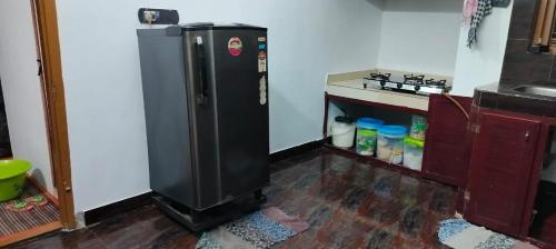 una cucina con frigorifero nero in camera di Bibgyor home stay a Bekal