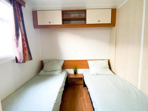 une petite chambre avec deux lits et une fenêtre dans l'établissement Camping Europcamping, à Fréjus