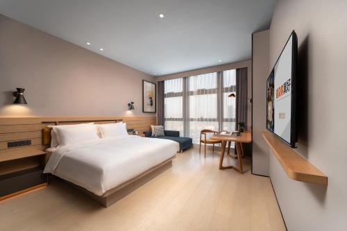 杭州市にあるSSAW Boutique Hotel Hangzhou Chengjunのベッド、デスク、テーブルが備わる客室です。