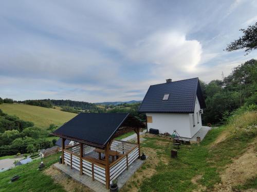 una casa bianca con un tetto nero su una collina di Sielska Osada - domki całoroczne a Rudenka