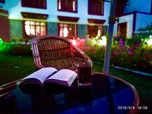 - une table en verre avec un livre et une boisson dans l'établissement Hotel Pangong Residency, à Leh