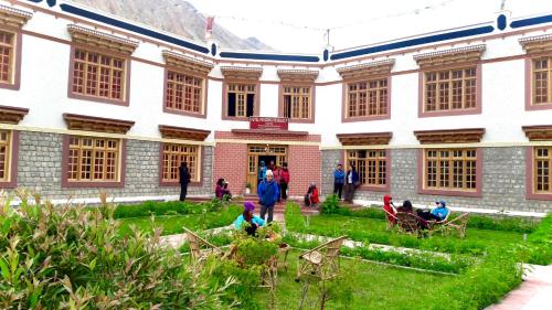 a group of people sitting in the grass in front of a building at Hotel Pangong Residency in Leh
