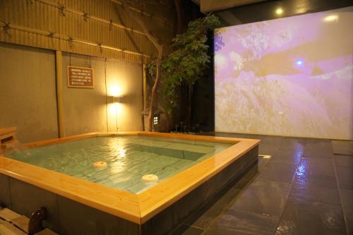 una gran piscina de agua en una habitación con una pintura en Hanasuishou en Fuefuki