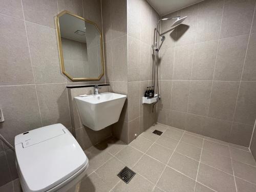 W łazience znajduje się toaleta, umywalka i lustro. w obiekcie Carlton Hotel Bupyeong w mieście Inczon