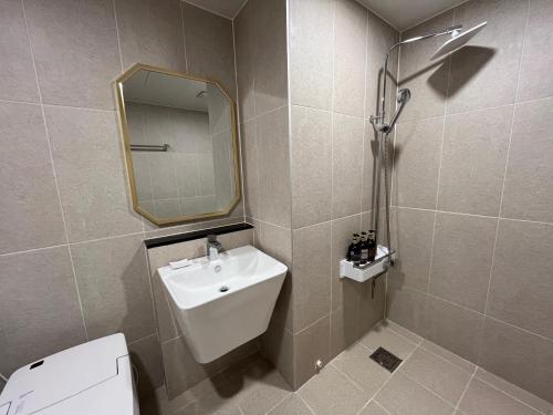 a bathroom with a sink and a mirror and a toilet at Carlton Hotel Bupyeong in Incheon