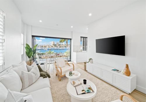 a living room with white furniture and a flat screen tv at Peach at Palm View Collective in Sydney
