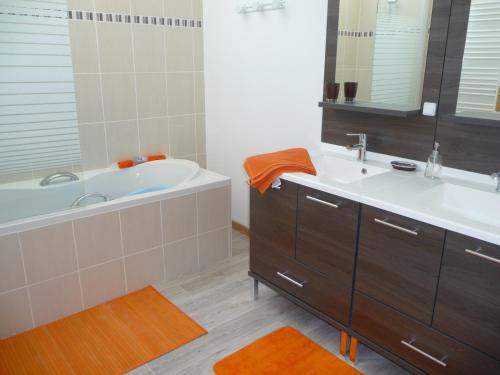 une salle de bain avec une baignoire, un lavabo et un miroir dans l'établissement La Vallée, à Feugères