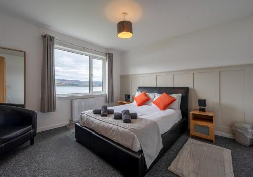 a bedroom with a bed with orange pillows and a window at Loch Ness Cottage in Fort Augustus