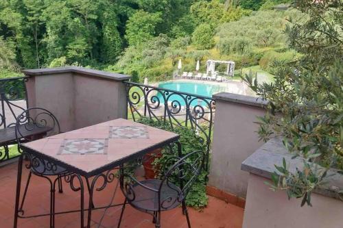 een tafel en stoelen op een balkon met een zwembad bij Il Conte, Alloggio romantico per Coppie + Piscina in Serravalle Pistoiese