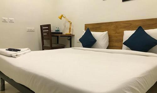 una camera da letto con un grande letto bianco con cuscini blu di FabHotel Rithik Heights Hitech City a Hyderabad