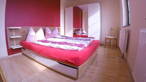 a bedroom with a large bed with a red wall at Ferienbauernhof - Ferienwohnung 6 in Grünow