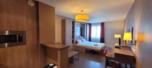 Habitación pequeña con cama y TV en City'O apparthotel en Caen