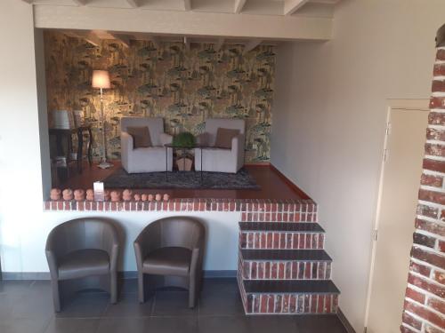 a living room with a staircase and chairs and a wall at Brabant17 in Poperinge