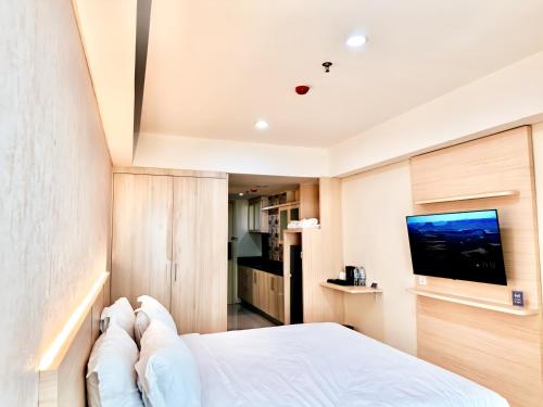 1 dormitorio con 1 cama blanca y TV de pantalla plana en KUMU Lantai 18 Warhol Residence at Louis Kienne Simpang Lima Semarang en Semarang
