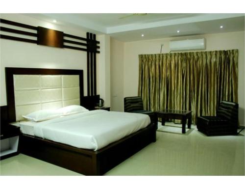 a bedroom with a bed and a table and chairs at Hotel Jasmine, Haridwar in Haridwār