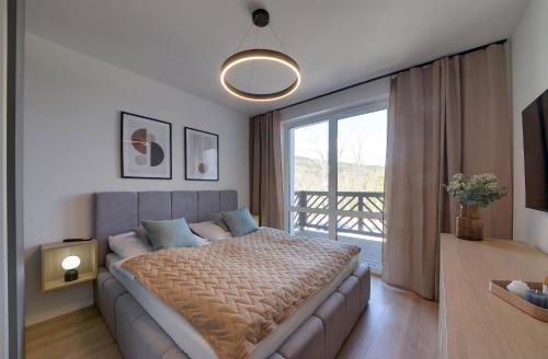 ein Schlafzimmer mit einem Bett und einem großen Fenster in der Unterkunft Trevilles Apartamenty Soft Loft in Szklarska Poręba