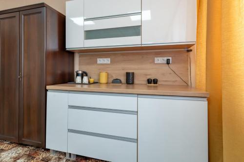 a kitchen with white cabinets and a wooden wall at Hostello - Pokoje, Bilard, Ping-Pong, Parking - by SpaceApart in Jelenia Góra