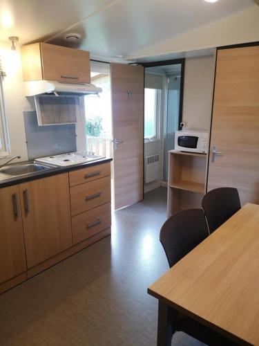 une cuisine avec des armoires en bois et une table avec des chaises dans l'établissement MOBIL HOME 6 Places - CLIMATISE, à Aureilhan