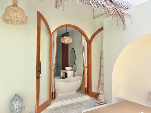 ein Badezimmer mit einer weißen Badewanne und einem Spiegel in der Unterkunft Tujuan Jogja Villas With Private Pool in Jetis