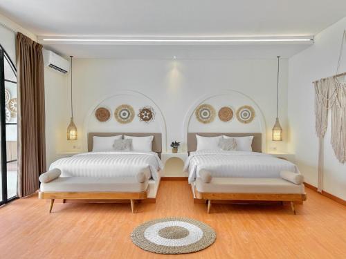 2 camas en un dormitorio con paredes blancas y suelo de madera en Tujuan Jogja Villas With Private Pool, en Jetis