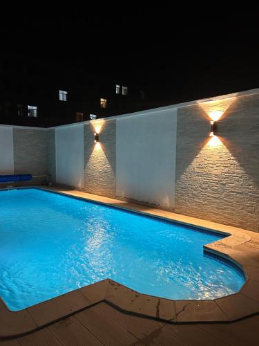 - une piscine la nuit avec des lumières sur le mur dans l'établissement ZARA HOTEL, à Antananarivo