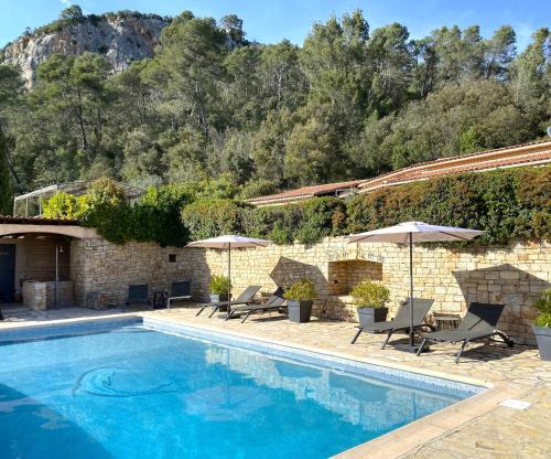 una piscina con sedie e ombrelloni accanto a un edificio di Le Mas de San Lou a Cabasse