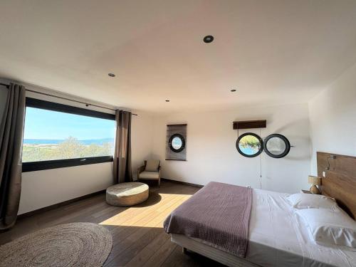 une chambre avec un grand lit et une grande fenêtre dans l'établissement NOUVEAUTE ! La Maison de la plage - tout confort avec jardin, à Propriano