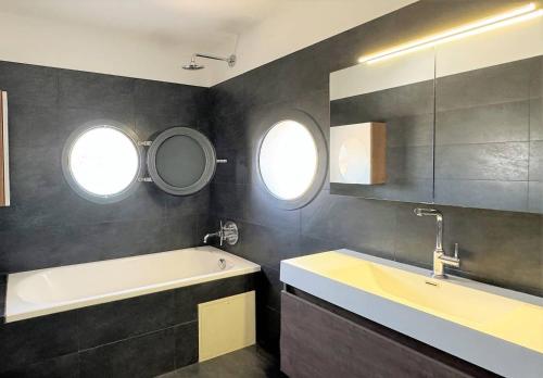 La salle de bains est pourvue d'une baignoire, d'un lavabo et de 2 fenêtres. dans l'établissement NOUVEAUTE ! La Maison de la plage - tout confort avec jardin, à Propriano