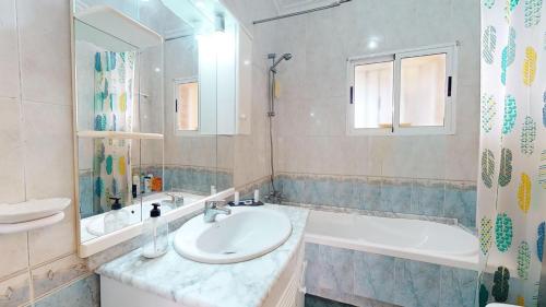 ein Badezimmer mit einem Waschbecken, einer Badewanne und einem Spiegel in der Unterkunft Villa Greenland-A Murcia Holiday Rentals Property in Los Alcázares