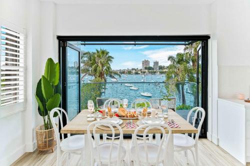 a dining room with a table and chairs and a view of the water at Phoenix at Palm View Collective in Sydney