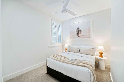 ein weißes Schlafzimmer mit einem Bett und einem Fenster in der Unterkunft Phoenix at Palm View Collective in Sydney