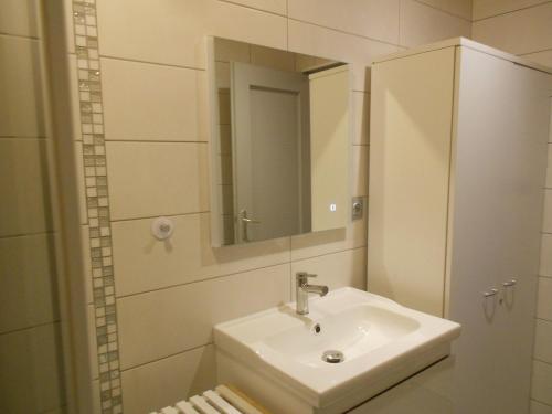 een witte badkamer met een wastafel en een spiegel bij bouton d or in La Bresse