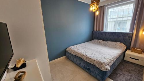 a small bedroom with a bed and a window at Apartamenty Klifowa in Rewal