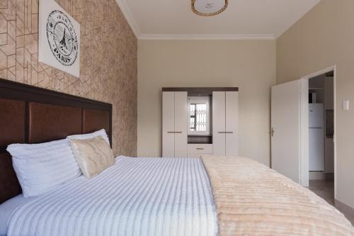 a bedroom with a large bed with white sheets at Evans Village - Apartments & Spa in Johannesburg