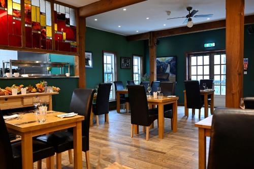 フォート・ウィリアムにあるLime Tree Hotelの木製のテーブルと椅子、緑の壁が備わるレストラン
