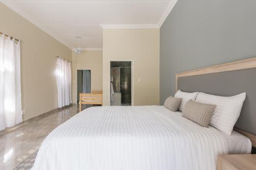 a white bedroom with a large white bed with pillows at Evans Village - Apartments & Spa in Johannesburg