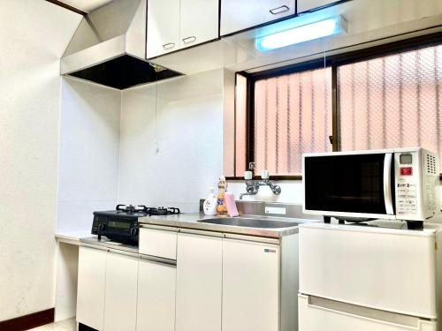 kuchnia z białymi szafkami i kuchenką mikrofalową w obiekcie KIBA HOUSE w Tokio