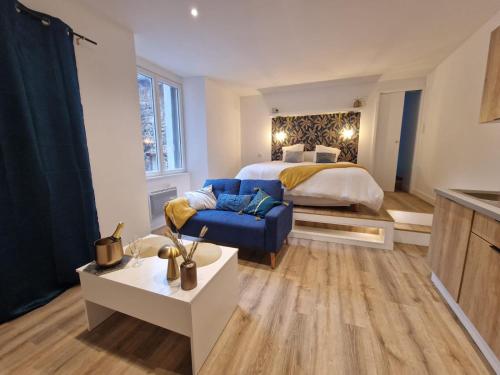 - une chambre avec un lit king-size et une chaise bleue dans l'établissement Lhôtel de la Poule et du Renard Appartement avec Balnéo terrasse dans le centre du vieux Millau, à Millau