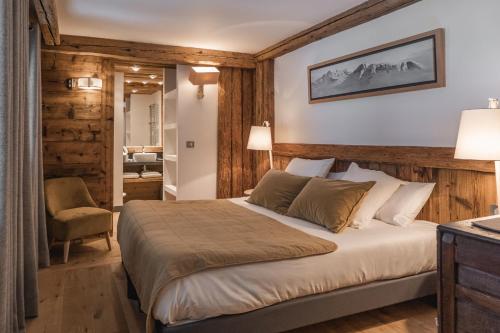 a bedroom with a bed and a chair at Chalet Papillon - LES CHALETS COVAREL in Val dʼIsère