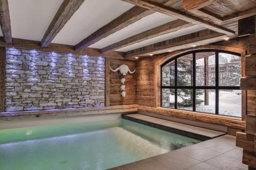 - une piscine dans une chambre dotée d'un mur en pierre dans l'établissement Chalet Papillon - LES CHALETS COVAREL, à Val dʼIsère