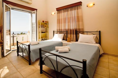 two beds in a room with a large window at Eirini's home in Kalymnos