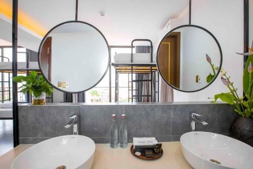 a bathroom with two sinks and two mirrors at Clover Home Quảng Bình in Dong Hoi
