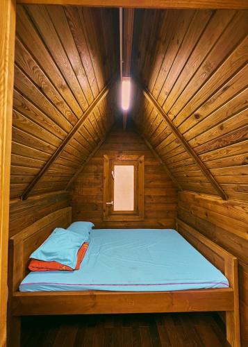 a bed in a wooden cabin with a light on it at Nhà Bao La - Hồ Đak Long Thượng in Bao Loc